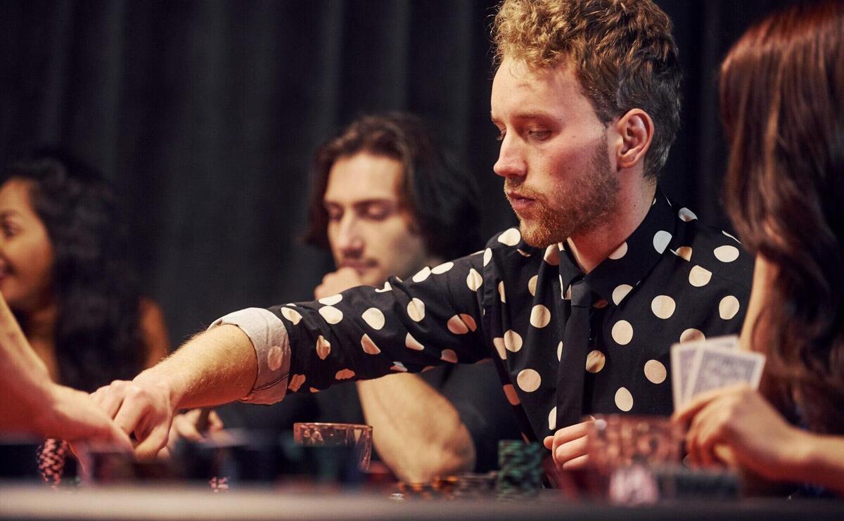 Group of elegant young people that playing poker in casino together