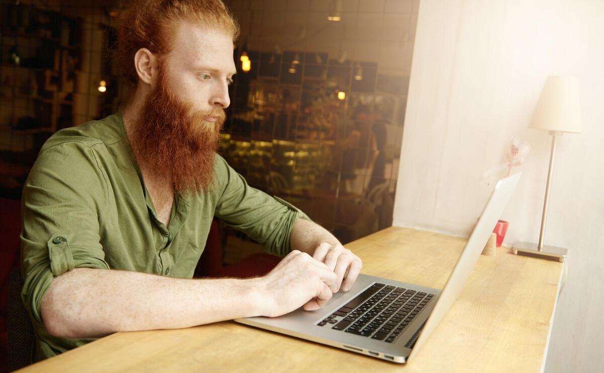 Young ginger man using laptop