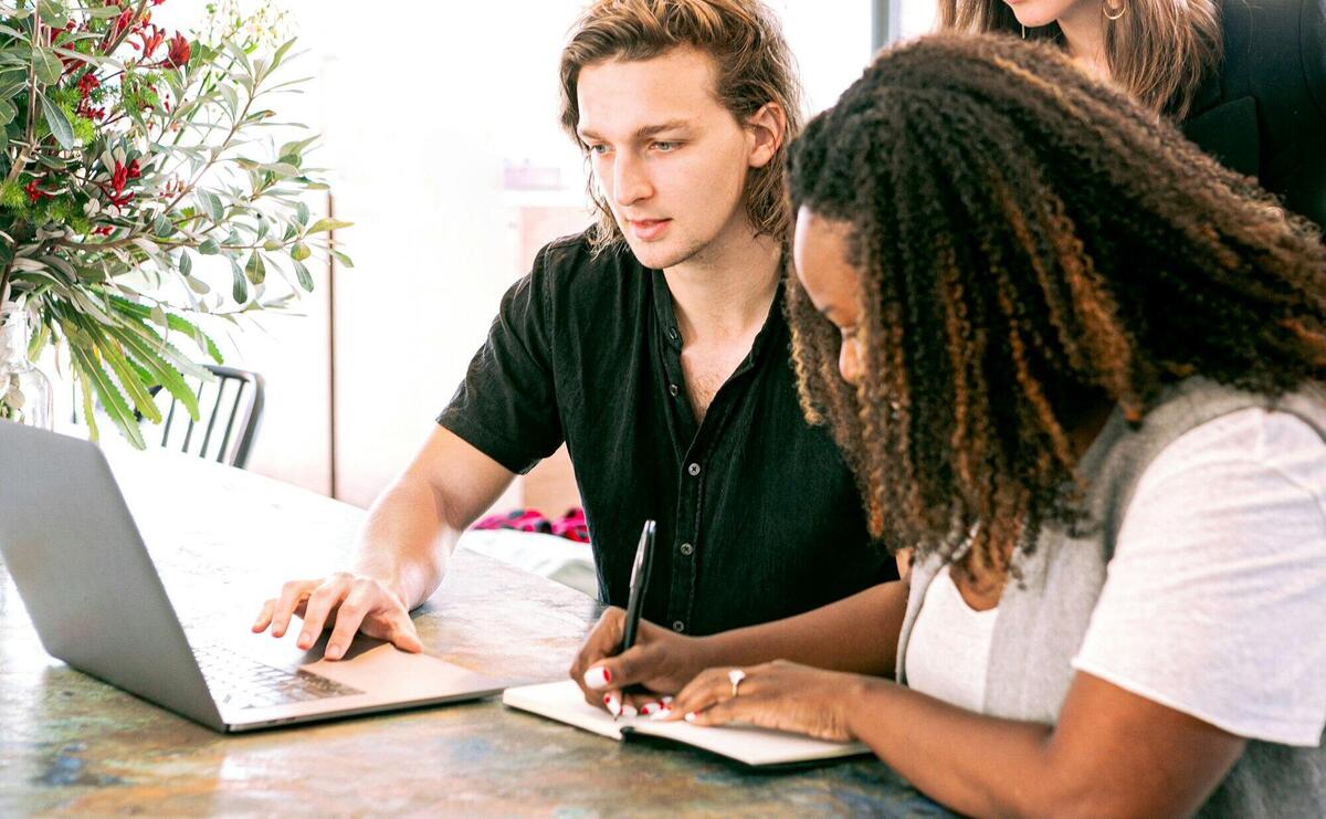 Young professionals collaborating on a project in a modern office with laptop and notes.